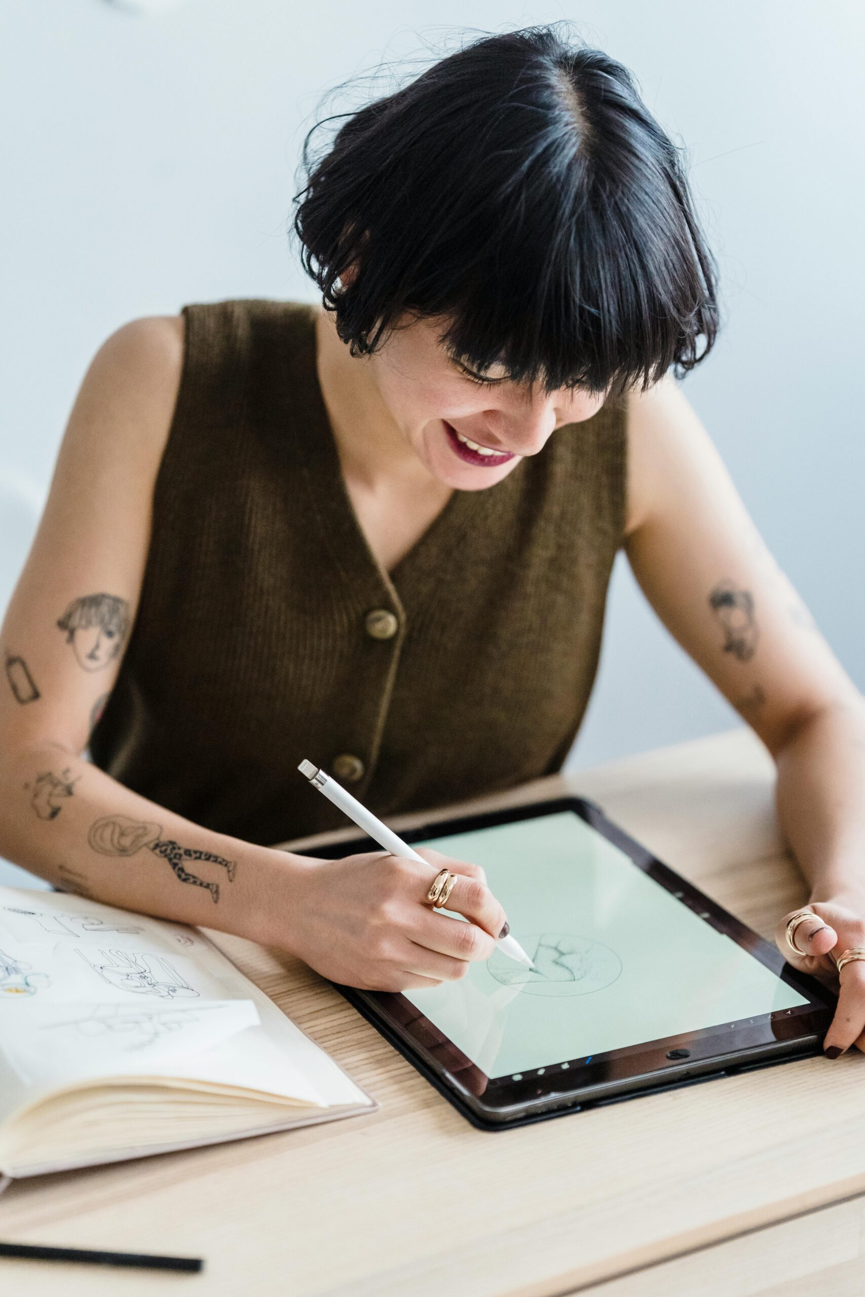 Young female artist drawing digitally with stylus, showcasing creativity in modern workspace.